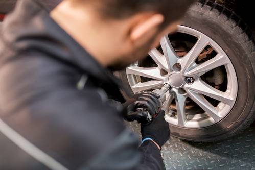 auto mechanic with screwdriver changing car tire 2024 09 27 21 30 32 utc 1 - Tegnene på, at dine dæk trænger til service – vent ikke for længe